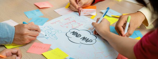 Professionelle Startup-Gruppe teilen kreative Marketing-Idee, indem sie Mindmap verwenden. Junge, qualifizierte Geschäftsleute erstellen Geschäftspläne, während sie klebrige Notizen schreiben. Konzentrieren Sie sich auf die Hand. Nahaufnahme. Bunt gemischt. - Foto, Bild