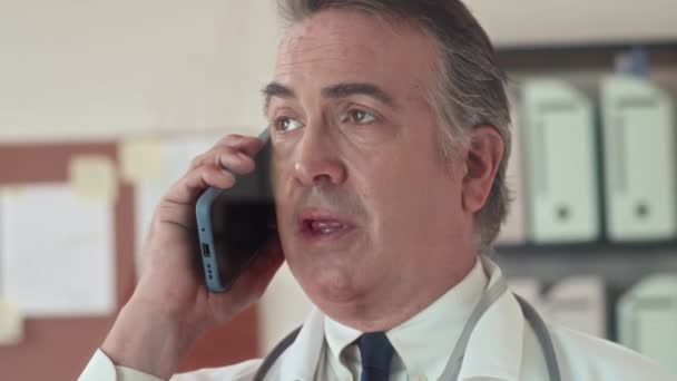 Close-up van volwassen huisarts bellen patiënt op mobiele telefoon en informeren over medische testresultaten, slow motion - Video