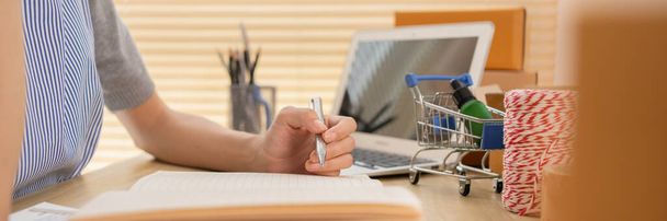 Vender productos en línea, Primer plano para la mano sosteniendo un bolígrafo y tomando notas en un cuaderno, Trabajo para el hogar. - Foto, imagen