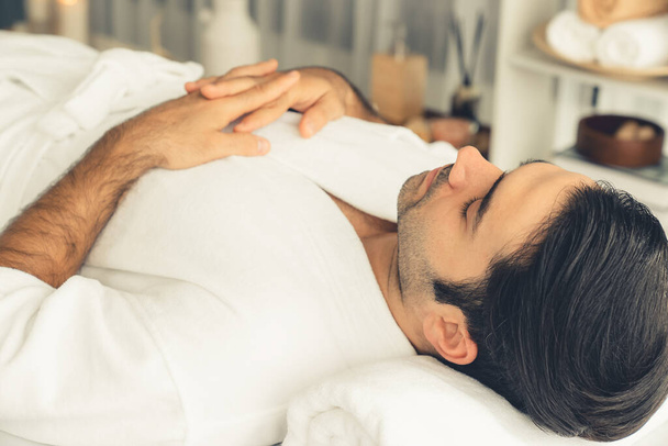 Kaukaski mężczyzna klient korzystających relaksujący masaż antystresowy spa i rozpieszczający z rekreacji skóry piękna rekreacji w dzień światło ambient salon spa w luksusowym ośrodku lub hotelu. Cichy zapach - Zdjęcie, obraz