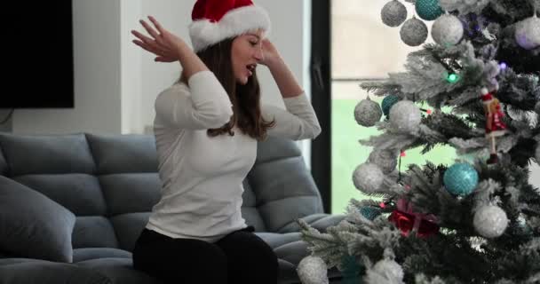Überraschte Frau holt Geschenk aus Zweig des geschmückten Weihnachtsbaums, der Weihnachten im Winter feiert. Freude und Freude am Feiern - Filmmaterial, Video