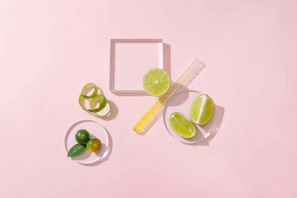 Glass platform, a petri dish, a test tube, fresh lemons and kumquats stand out on a light pink background. Space for displaying natural cosmetics with lemon extract. - Photo, Image