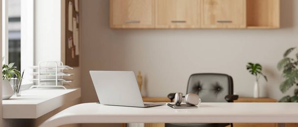 Ein modernes und minimalistisches Homeoffice oder privates Büro mit Laptop, Kopfhörer und einem Buch auf einem weißen Schreibtisch. 3D-Renderer, 3D-Illustration - Foto, Bild
