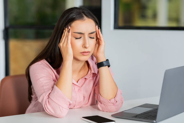 疲れたミレニアル世代のアラブ人女性マネージャーは,ノートパソコンの仕事上の問題,コワーキングオフィスの頭痛に苦しんでいます. ビジネス,片頭痛,プレッシャーのストレス,期限 - 写真・画像