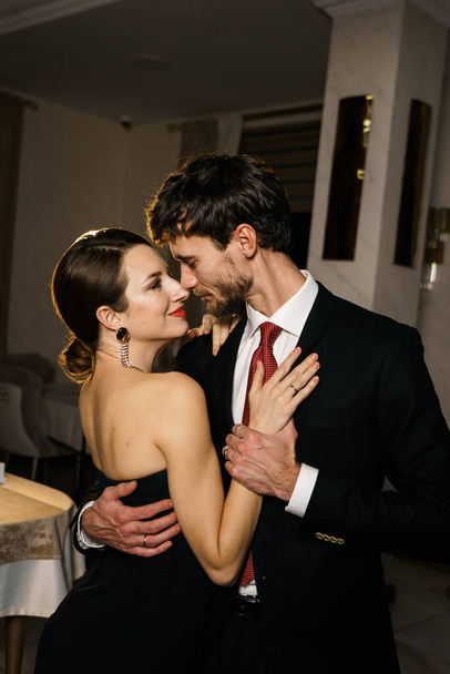 Um homem e uma mulher elegantes em trajes noturnos, um terno e um vestido, posando contra o pano de fundo de um luxuoso hotel. Conceito de casino - Foto, Imagem