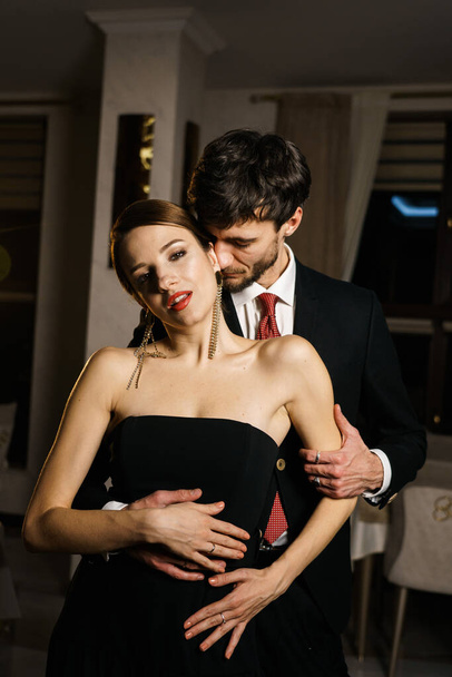 Un hombre y una mujer con estilo en ropa de noche, un traje y un vestido, posando sobre el telón de fondo de un hotel de lujo. Concepto Casino - Foto, imagen