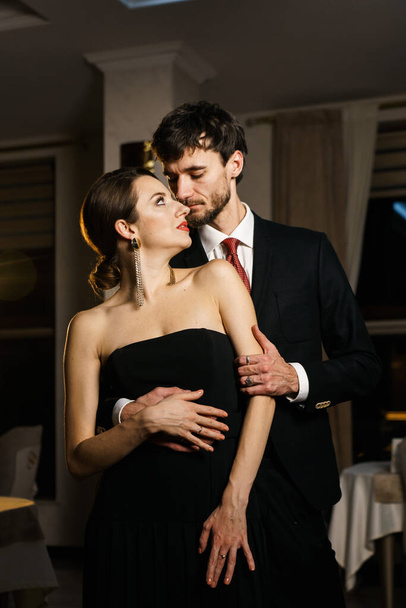 Un hombre y una mujer con estilo en ropa de noche, un traje y un vestido, posando sobre el telón de fondo de un hotel de lujo. Concepto Casino - Foto, imagen