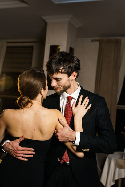 Un hombre y una mujer con estilo en ropa de noche, un traje y un vestido, posando sobre el telón de fondo de un hotel de lujo. Concepto Casino - Foto, Imagen