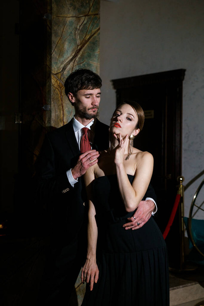 Стильный мужчина и женщина в вечерней одежде, костюме и платье, позируют на фоне роскошного отеля. Концепция казино - Фото, изображение