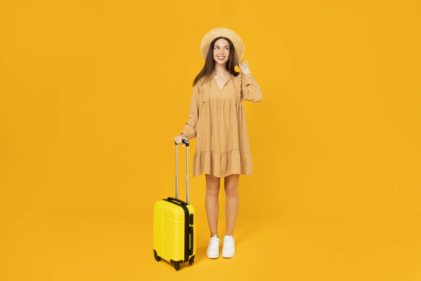 Giovane ragazza con una valigia su uno sfondo giallo. - Foto, immagini