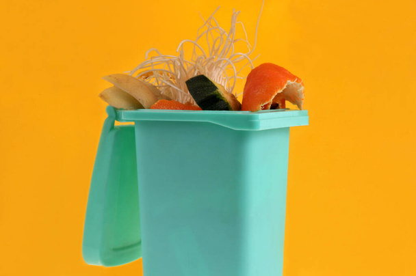 Kompostierungskonzept mit einem Mülleimer voller Biomüll in Großaufnahme auf gelbem Hintergrund  - Foto, Bild