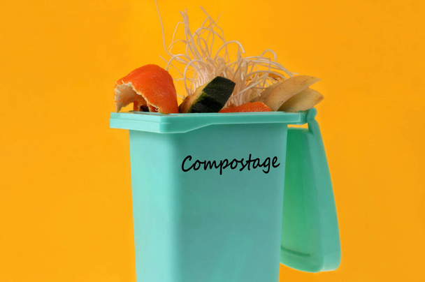 Concepto francés de compostaje con un bote de basura lleno de residuos orgánicos de primer plano sobre fondo amarillo - Foto, imagen