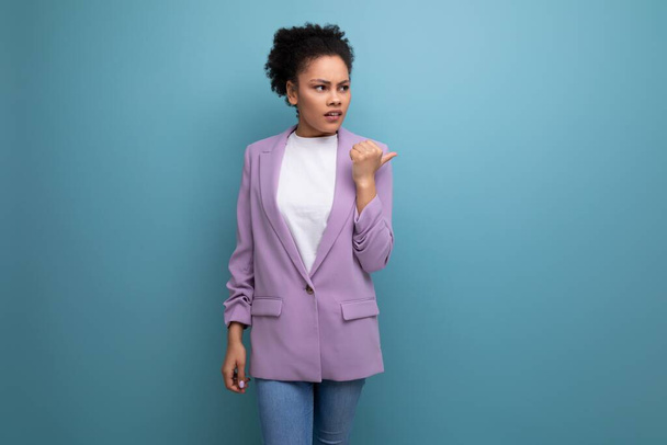 コピースペース付きスタジオバックグラウンドで紫のジャケットを着たポニーテールヘアスタイルの若いラテン系ビジネス女性. - 写真・画像
