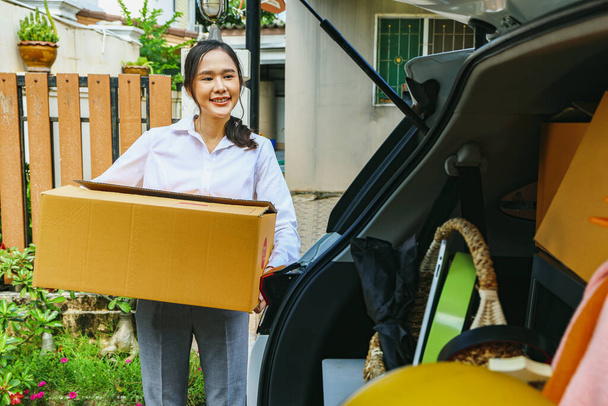 Happy good mood asian businesswoman neatly carries cardboard boxes and moves her daily necessities into the back of her truck preparing to move house and driving new, more convenient place to live. - Photo, Image