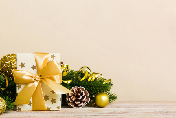 Новогоднее настроение, подарочная коробка, ветви елки, новогодние украшения на цветном фоне. - Фото, изображение