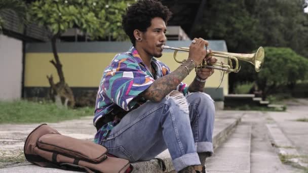 Joven practicando jazz, tocando trompeta al aire libre en el parque - Metraje, vídeo