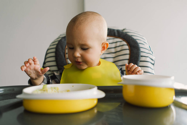 Małe dziecko z solidnym odżywianiem. Dziewczynka je paluszki i miesza warzywa. Baby doprowadziły do odstawienia BLW samodzielnego karmienia. - Zdjęcie, obraz