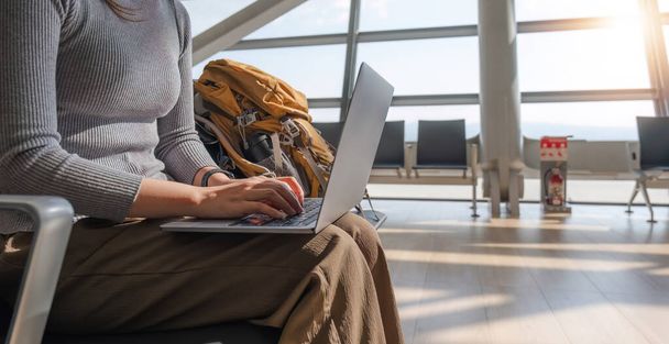 Giovane donna asiatica che utilizza il computer portatile per controllare gli orari dei voli in aeroporto per le vacanze. - Foto, immagini