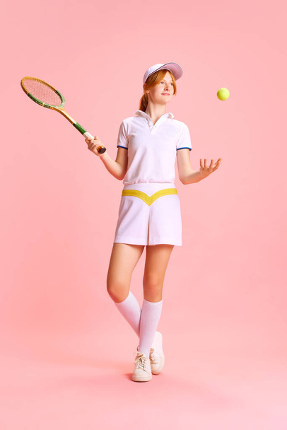 Retrato completo de mulher bonita e confiante, jogador de tênis joga bola com uma mão contra fundo rosa pastel. Conceito de esporte profissional, recreação, hobby, campeonato. - Foto, Imagem