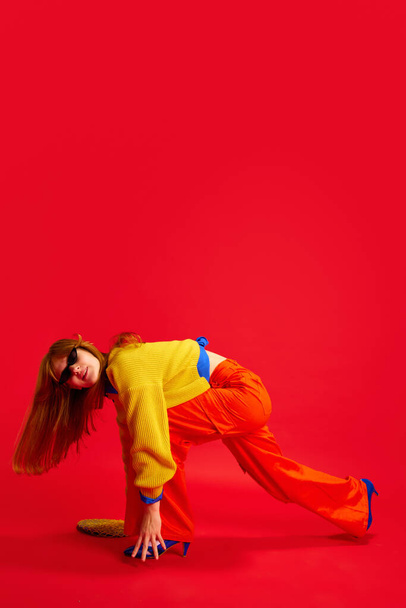 Retrato extraordinario creativo de la joven divertida, adolescente vestido traje de moda retro posando sobre fondo rojo vivo. Concepto de emociones humanas, moda moderna, estilo de vida, tendencias de estilo. - Foto, Imagen