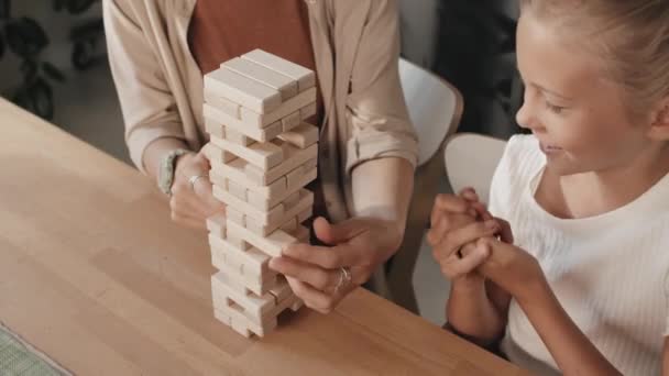 Hoge hoek slow motion van moeder en dochter genieten van bordspel met houten blok toren - Video