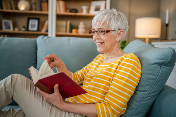 Jedna žena zralý senior kavkazský žena důchodce moderní babička číst knihu doma nosit brýle skutečný člověk kopírovat prostor - Fotografie, Obrázek