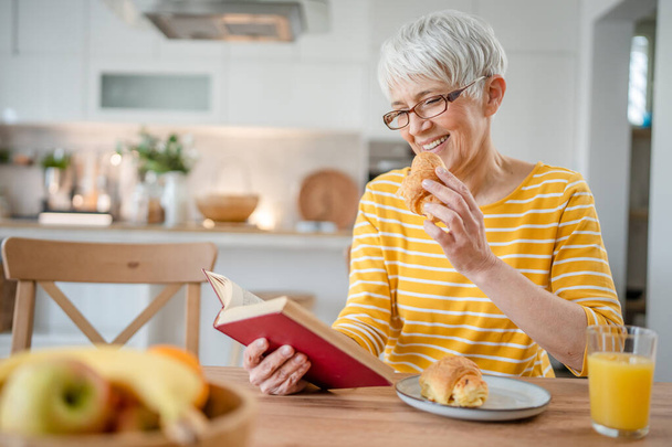 Eine Frau reif Senior kaukasischen Rentnerin moderne Großmutter lesen Buch zu Hause tragen Brille echte Person Kopierraum - Foto, Bild
