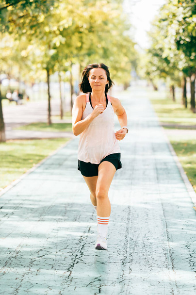 Függőleges fénykép sport nő fut a parkban reggel. - Fotó, kép