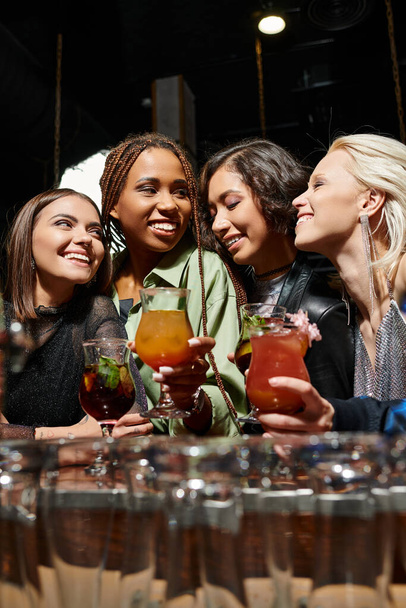 αριστοκρατικό και χαρούμενο φίλες κρατώντας ποτήρια με νόστιμα κοκτέιλ στο μπαρ, αναψυχή - Φωτογραφία, εικόνα