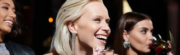 Viettelevä blondi nainen hymyilee lähellä cocktail-lasia ja monikansallisia tyttöystäviä baarissa, banneri - Valokuva, kuva