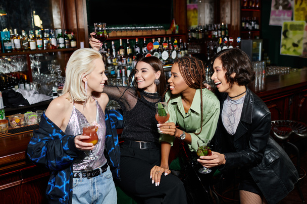 gondtalan többnemzetiségű női barátok koktélokat tartanak és beszélgetnek a modern bárban, buliznak - Fotó, kép
