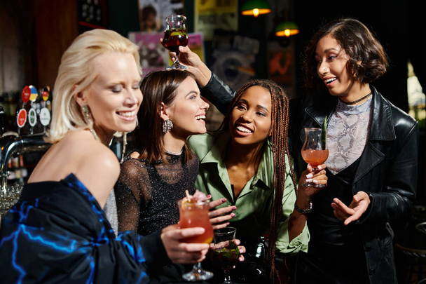 boldog ázsiai nő pohárköszöntő koktéllal közel elbűvölő multietnikus barátok a bárban, szórakoztató idő - Fotó, kép