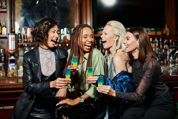 захоплені багаторасові друзі-жінки з розстріляними окулярами сміються в сучасному барі, час вечірки - Фото, зображення