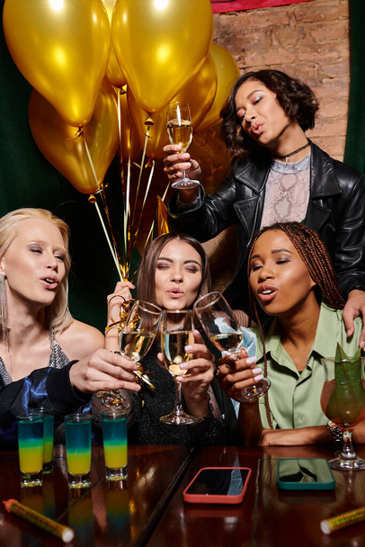 rozmanitá skupina multietnických přítelkyň cinkající sklenice šampaňského během narozeninové párty v baru - Fotografie, Obrázek