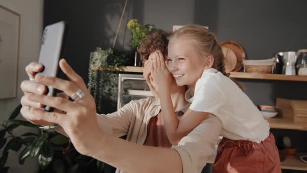 Veselý matka drží smartphone přičemž legrační selfie se svou krásnou předpubertální dceru, zatímco tráví čas doma - Záběry, video