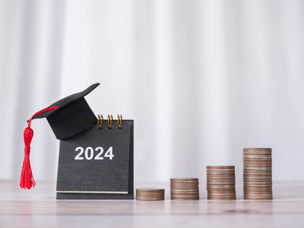Objetivos do estudo, 2024 Calendário de mesa com chapéu de graduação e pilha de moedas. O conceito de poupar dinheiro para a educação, empréstimo estudantil, bolsa de estudos, propinas no Ano Novo 2024 - Foto, Imagem
