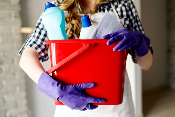 Close-up de mãos de mulher segurando balde cheio de limpadores
 - Foto, Imagem