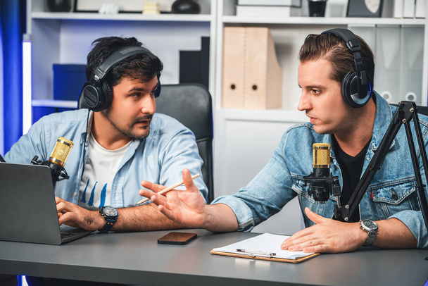 Host channel of creative broadcaster living by smartphone in positive podcast with special guest in list script to advice listeners, wearing headsets, using mic radio record at studio. Sellable. - 写真・画像