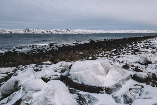 Pláž s kulatými kameny v zamračený den. Pobřeží Severního ledového oceánu v blízkosti obce Teriberka. Murmanská oblast, Rusko - Fotografie, Obrázek