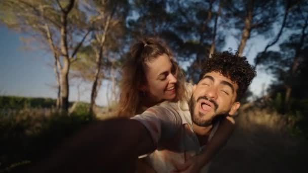 Dos amantes sonríen y se toman fotos en un bosque - 4K Horizontal video - Imágenes, Vídeo