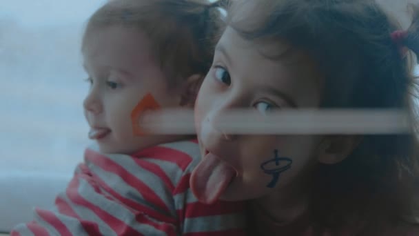 Due allegre bambine con simboli di comunicazione dipinti sul viso. Facendo facce strane. Concetto di comunicazione - Filmati, video