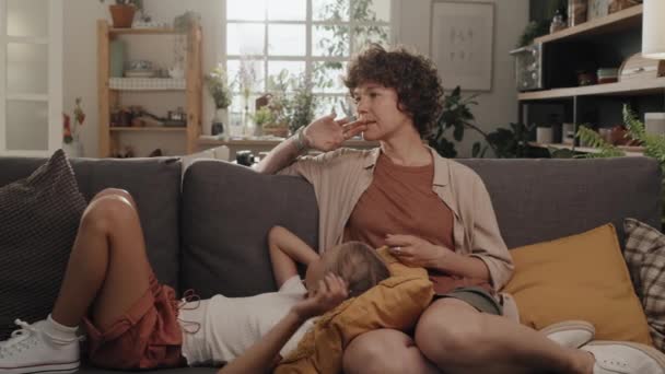 Moderne alleinerziehende Mutter, die Zeit zu Hause mit ihrer Tochter verbringt, die es sich auf dem Sofa gemütlich macht und über etwas spricht, Zeitlupenaufnahme - Filmmaterial, Video
