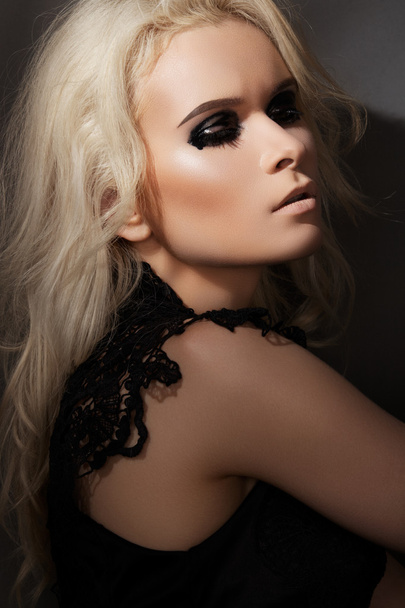 Beautiful blond woman model in chic lacy black dress - 写真・画像