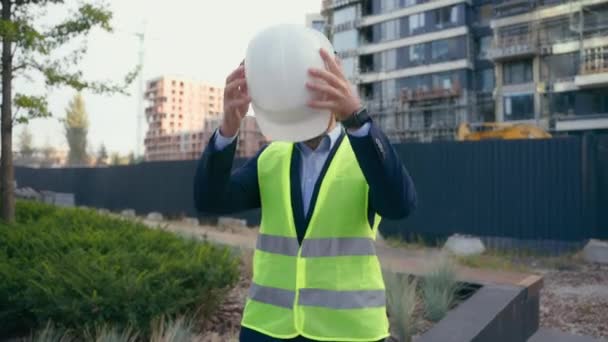 Serious Kavkazský středního věku dospělý budova urbanistická stavba developerská nemovitost realitní architekt muž stavitel dodavatel opravář dát na helmu bezpečné práce uniforma ochrana proti opotřebení ochranný hardhat - Záběry, video