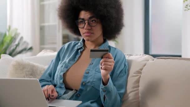 Αφρο-αμερικανός στοχαστικός πελάτης γυναίκα αγοραστής κορίτσι κοπέλα σκέφτεται σκεπτικός αποφασίσει να αναλογιστεί ψώνια με φορητό υπολογιστή και τραπεζική πιστωτική κάρτα σκέφτονται πληρωμής στο διαδίκτυο αγοράζουν αγαθά παραγγελία στο σπίτι - Πλάνα, βίντεο