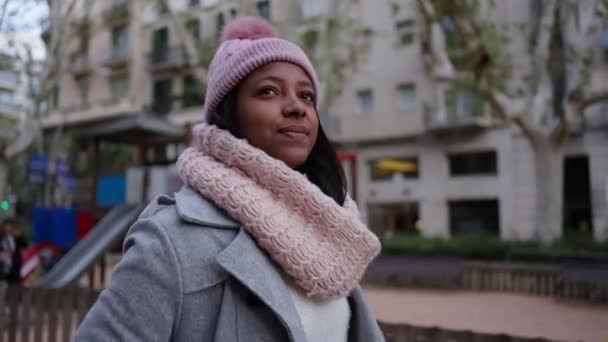 Sebevědomá mladá žena v zimním oblečení a klobouku kráčející venku s pozitivním výrazem. Usmívající se a veselá žena přecházející městskou čtvrť v městské ulici. Lidé na cestě na schůzku - Záběry, video