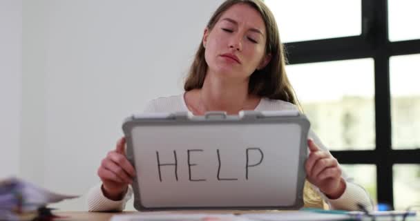 Sullen γυναίκα δείχνει λέξη Βοήθεια γραμμένο σε φορητό λευκό πίνακα ως ένδειξη της έκκλησης για σωτηρία. Αντιπαθητική εργασία και ταλαιπωρία από την ολοκλήρωση εργασιών από το αφεντικό αργή κίνηση - Πλάνα, βίντεο