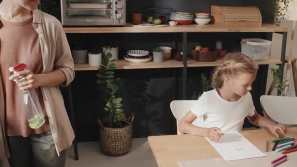 Wesoły biały kobieta patrząc na obraz jej córka rysuje podczas wykonywania prac domowych w kuchni - Materiał filmowy, wideo