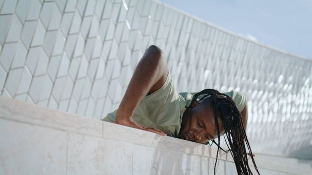 Contemporary choreographer practicing at abstract building. African american man showing flexible jazz dance at urban settings. Dreadlocks sportsman training outdoors. Active dancer improvising - Photo, Image