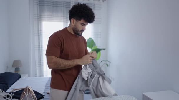 Homem latino se concentra em passar as calças - 4K Horizontal vídeo - Filmagem, Vídeo